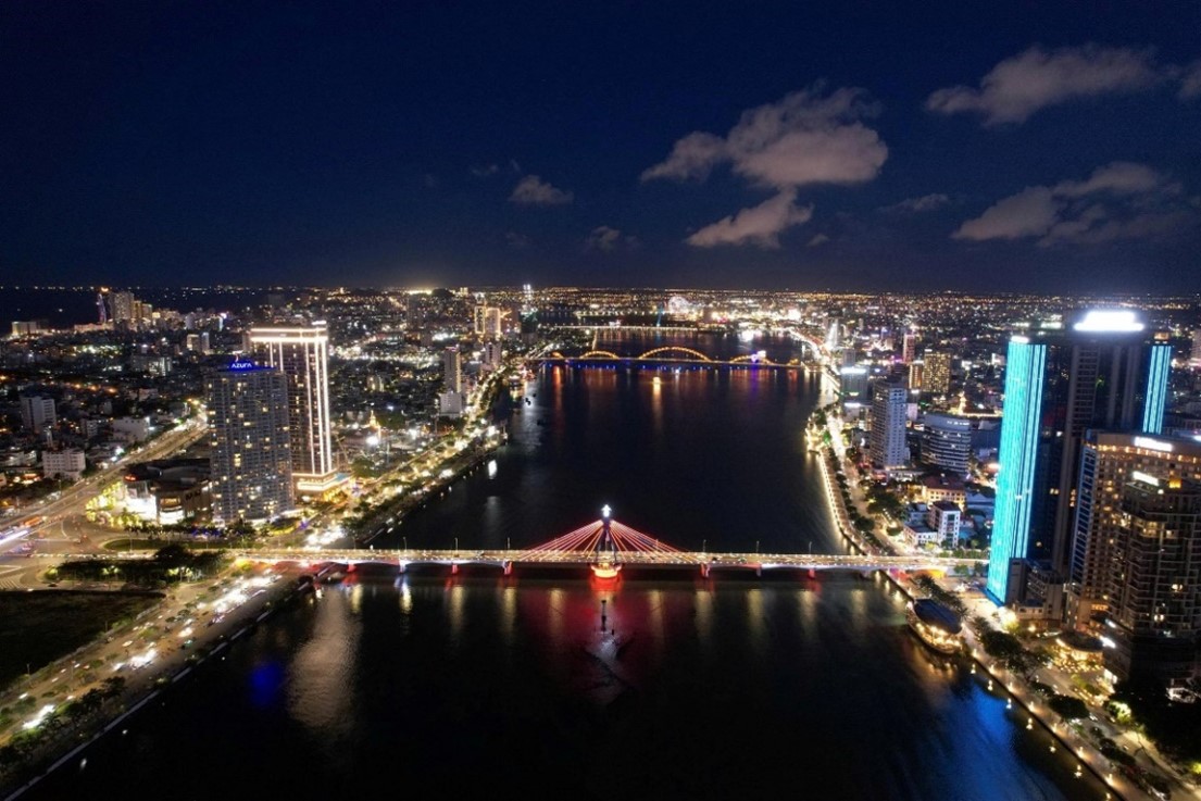A cityscape at night with a bridge and a riverDescription automatically generated